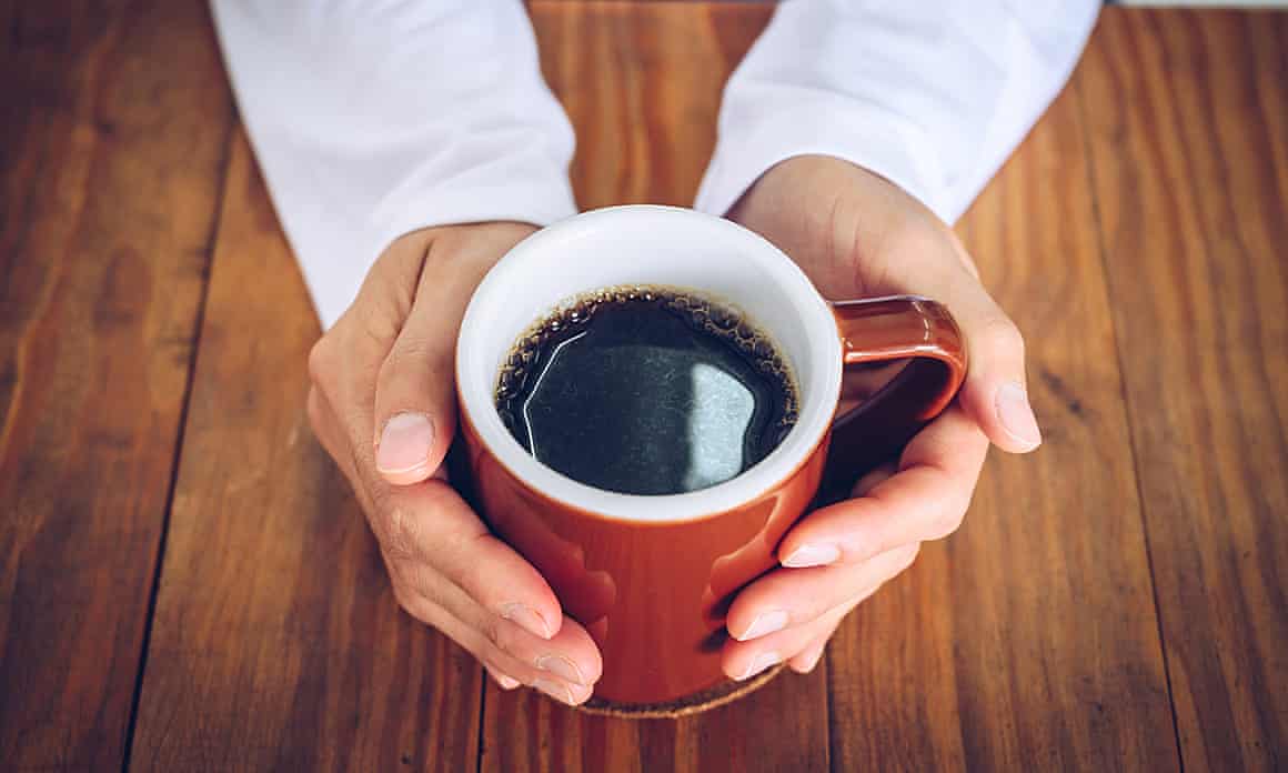 Hands holding a mug of black coffee