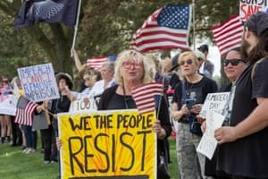 Protesters holding US flags and banners with slogans including ‘we the people resist’