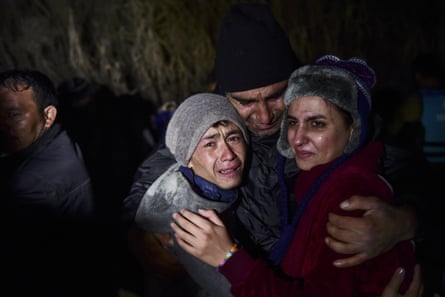 A man hugs his daughter and son on the Greek island of Lesbos.