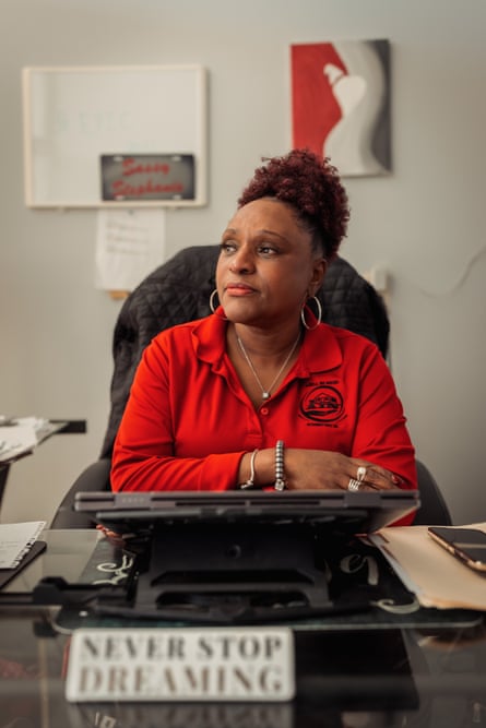 woman in red shirt sits at desk and looks to the side