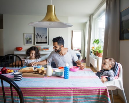A man sitting at a dining table next to a baby and a toddler
