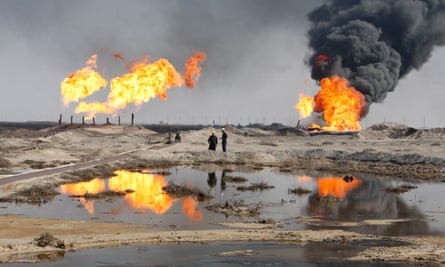 Excess gas is burned off near workers at the Rumaila oil field, south of Basra