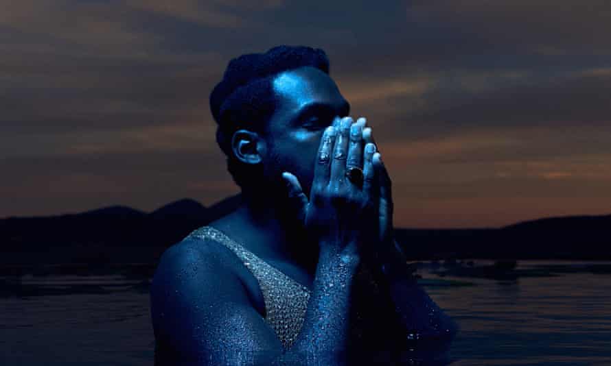 Leon Bridges in dark water against a sunset sky