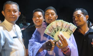 A resident shows off the 200,000 rupiahs he earned for catching 10 live rats during a pilot programme in Kemayoran, Jakarta, last month.