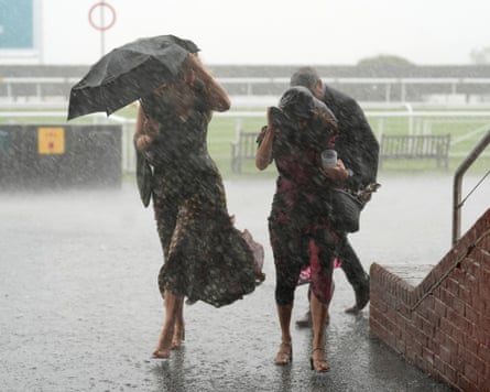 Racegoers do their best to shelter from the rain.