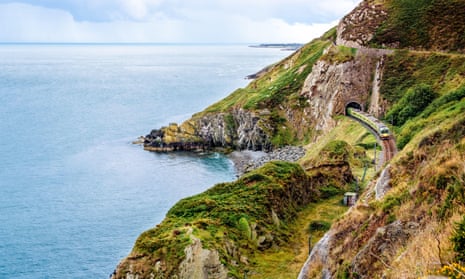 Train exiting a tunnel on Ireland’s east coast with beautiful coastline, cliffs and sea