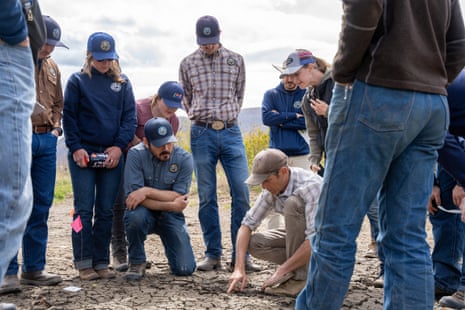 Group of people, some standing, some kneeling in dirt