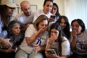 Nine people gather around a smartphone during a video call to one of the released hostages
