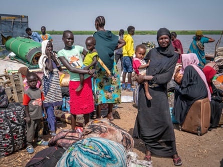 In the absence of humanitarian aid, women and children wait in the port of Renk with their luggage, hoping to catch a boat to Malakal.