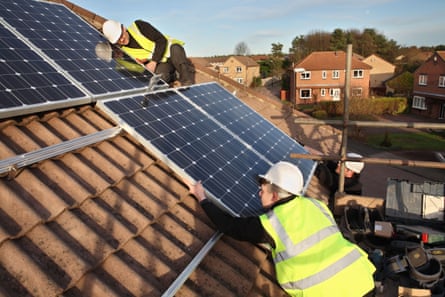 Construction workers in high-vis install solar panels on a house