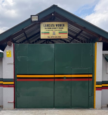 An building with iron gates and a peaked roof, from which hangs a sign saying ‘Lang’ata women maximum security prison’