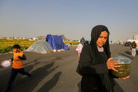 On the Beirut seafront, a young girl carries food in a plastic pot she received from a local NGO distributing hot dishes to people who fled south Lebanon