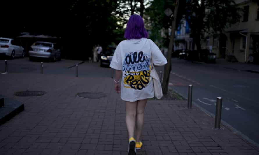 A woman walks down a street wearing a T-shirt reading ‘All we need is peace’ in Kyiv, Ukraine.