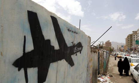 Yemenis walk past graffiti showing a US drone.