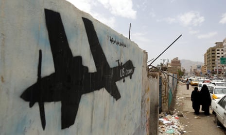 Yemenis walk past graffiti showing a US drone
