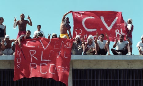 Men hold up red-and-white homemade signs that say "CV," among other things, with a clear blue sky behind them.