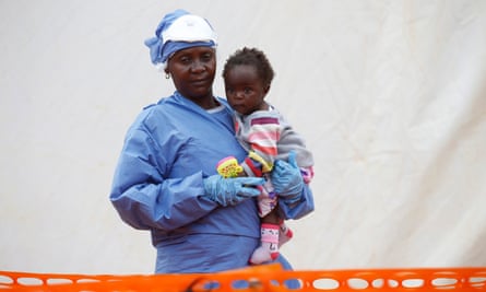 Victorine Siherya, an Ebola survivor working as a caregiver to babies who are confirmed Ebola cases, holds an infant outside the red zone at the Ebola treatment centre in Butembo