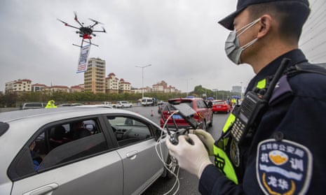 A police officer operates a drone carrying a QR code for drivers to register their vehicles online when entering Shenzhen, China.