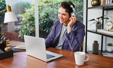 A man listening to headphones smiling at his computer.