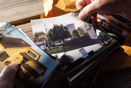 Fingers flipping through photographs of houses, some with a billowing coal plant in the background