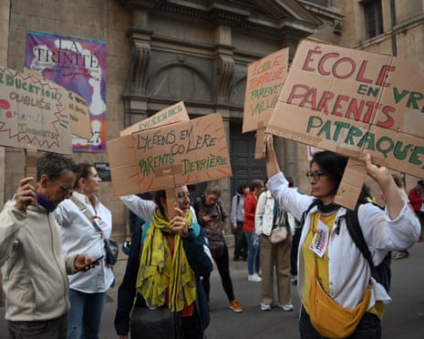 Parents of pupils hold placards, one reading “Angry high-school students, parents behind them” in front of the Ampere high school in Lyon.