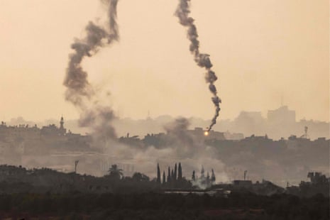 Smoke billows from the Israeli bombardment of Gaza as a flare fired by Israeli forces falls at a position near Israel’s southern border.