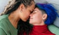 Horizontal top view of hispanic young gay women kissing in the couch at home. Lgbt community lifestyle indoors.