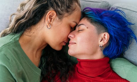 Horizontal top view of hispanic young gay women kissing in the couch at home. Lgbt community lifestyle indoors.