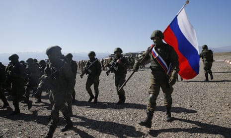 A group of Russian soldiers walk in the desert, carrying a Russian flag during a military drill in Balykchi, Kyrgyzstan