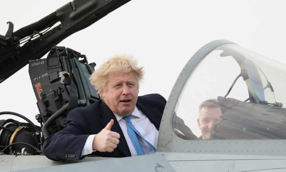 Boris Johnson gives a thumbs-up sign sitting in the cockpit of a jet fighter at an RAF base