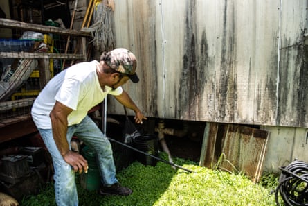 a man couches down and points to a wooden fence