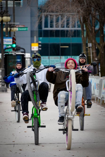 A group of cyclists do wheelies.