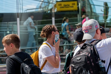 A tourist using a cold water can to try keep cool in the queue for the London Eye on the south bank in London.