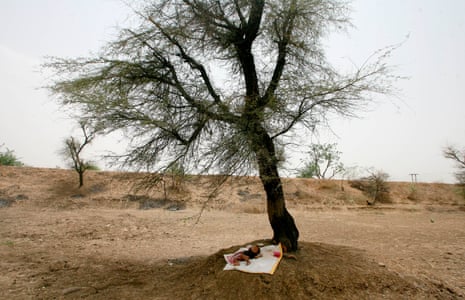 A baby lies under a tree as his mother works on a construction site near Abu Road, in the northern Indian state of Rajasthan.