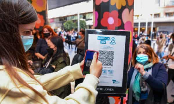 People scan a QR code to enter a department store in Melbourne.