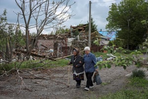 Two residents pass damaged buildings