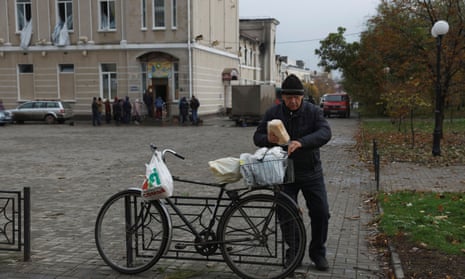 A man stands next to his bike as people, who come from their underground shelters, receive bread, as Russia’s invasion of Ukraine continues, in the eastern Donbas region of Bakhmut, Ukraine, October 30, 2022.