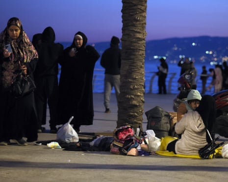 Displaced residents from Beirut’s southern suburb sit on the ground at Corniche Al Manara in Beirut.