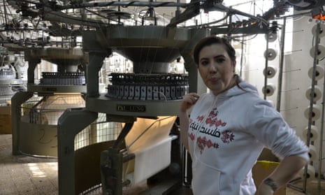 Tamara Alarja stands next to the fabric weaving machine inside her family factory in Palestine.