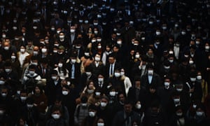 Mask-clad commuters make their way to work during morning rush hour at the Shinagawa train station in Tokyo.