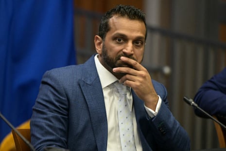a man in a suit sits with his hand over his mouth