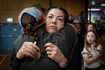 Two women embrace as children look on