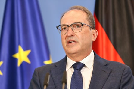 The federal minister of the interior, Alexander Dobrindt, speaks at a podium behind Europe and German flags