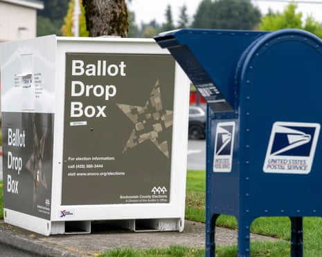 A white ballot drop box stands beside a blue USPS mail collection box in Bothell, Washington