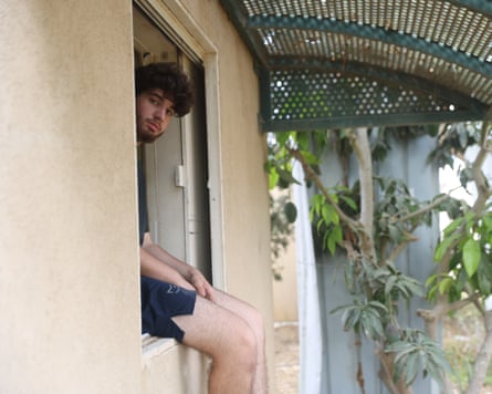 Young man sat in windowsill looks at camera