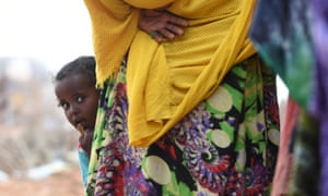 A child peers out from behind her mother as they wait for food aid in Gumar, Somaliland, where villagers are suffering form famine and drought.
