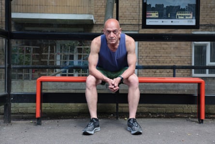 Phil Daoust, dressed in running gear, sits on a bench at a bus stop.