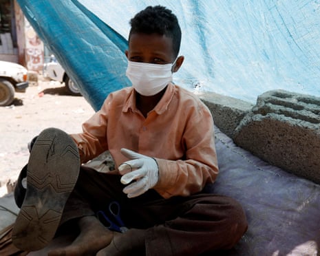 A child shoemaker wears a face mask and gloves to protect against Covid in Sanaa, Yemen