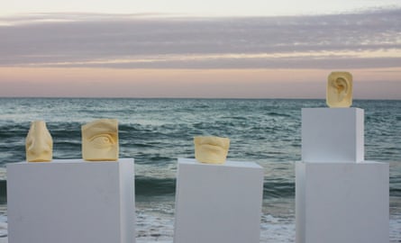 Body parts carved out of butter, on plinths, by the ocean