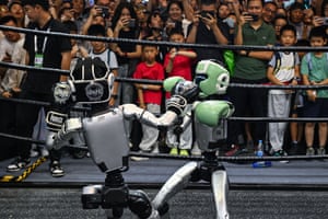 People watch a boxing match between two remote-controlled robots
